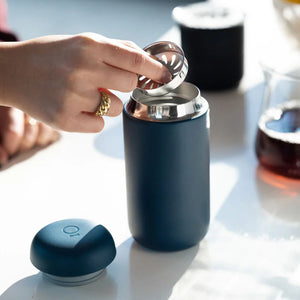 Mano que coloca un filtro en una taza de café reutilizable azul mate, parte de Take away y EspressoGear, todo sobre café.