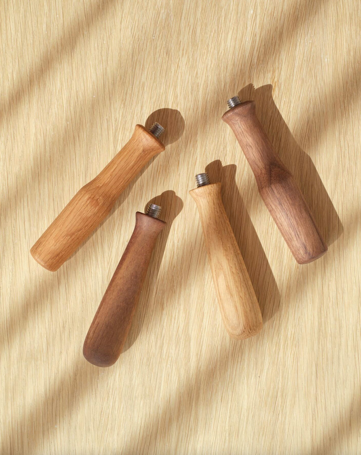 Fyra trähandtag med metallfäste för espressobryggare i naturligt ljus på träyta.