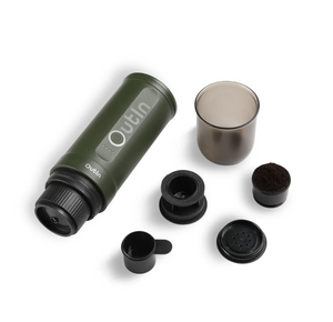 Cafetera espresso portátil en verde bosque con accesorios, perfecta para uso al aire libre y preparación manual.